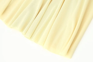Detailed macro view of light yellow pleated chiffon fabric with elegant texture
