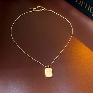 Detail shot of gold titanium steel square pendant necklace on a premium leather surface