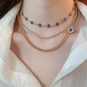 Close-up of gold layered necklace with blue evil eye pendants and rhinestone accents