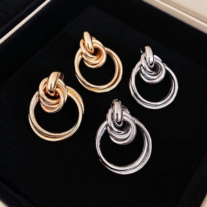 Polished intertwined circular earrings in gold and silver finish on black velvet display