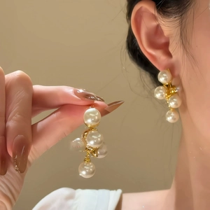 Elegant french geometric pearl drop earrings with gold finish on model and hand