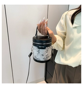 Detail of black cylindrical bucket bag featuring white lace embroidery and PU leather