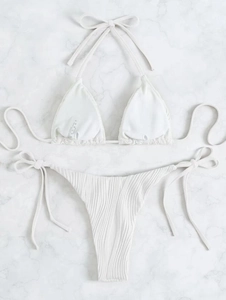 Dettaglio bikini bianco a coste con laccetti regolabili su sfondo in marmo pregiato