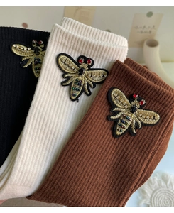 Detailed view of striped socks featuring luxury 3D bee embroidery in three colors