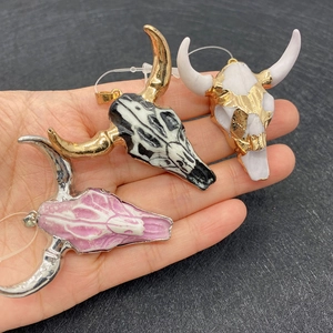 Three acrylic bull skull pendants in pink, blue, and white with metal horn accents
