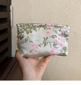 Macro shot of satin cosmetic bag with pale green silk texture and cherry blossom pattern