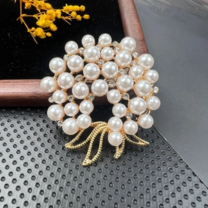 Close-up of elegant gold wreath brooch with white pearls and sparkling crystal bow details