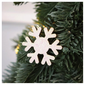 Close-up of sparkling white and pink glitter snowflake wooden ornament on Christmas tree branch