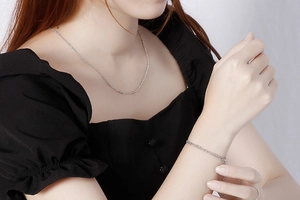 Detail of silver curb chain necklace and bracelet set with small beads on a model