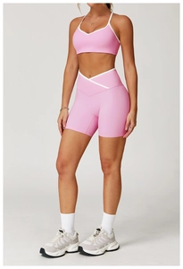 Detail van roze yoga short met gekruiste hoge taille, witte bies en sportbeha