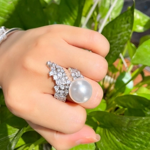 Macro view of a large white pearl ring with pavé diamond accents on a silver band