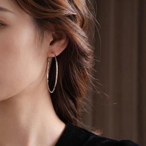 Boucles d'oreilles créoles argentées texturées avec finition martelée sur modèle