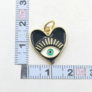 Detail of heart evil eye pendant in black enamel with ruler showing 2cm size