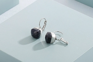 Macro detail of square blue goldstone earrings with silver leverback closure on a stand