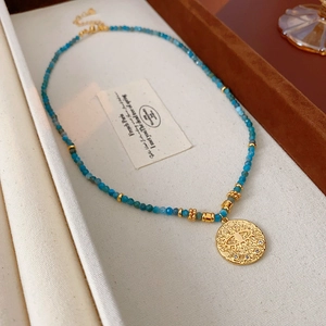 Detailed macro view of blue beaded necklace with vintage gold sunburst eye pendant