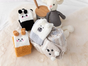 Flat lay of cute cartoon animal plush over-knee socks in four styles on a soft rug