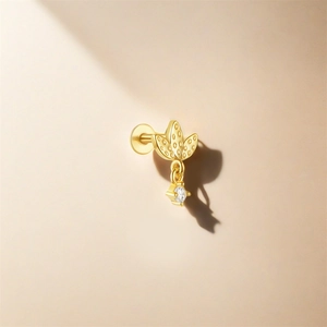 Detail of gold leaf stud earring with hanging crystal on a minimalist background