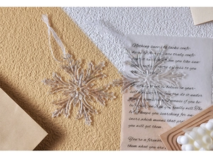 Close-up of two transparent acrylic snowflake ornaments with white ribbons for Christmas