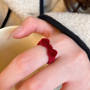 Detail of red flocked velvet bow ring on hand with warm cozy winter aesthetic