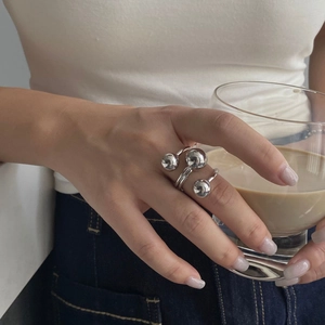 Close-up of a triple-layered silver sphere ring worn by a model holding a latte cup