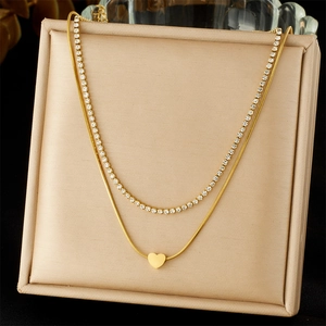 Detail of gold double-layered necklace with sparkling tennis chain and heart pendant