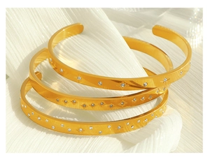 Detailed view of three 18K gold plated cuff bangles with cubic zirconia star patterns