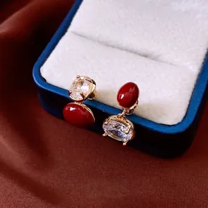 Boucles d'oreilles ovales rouges vintage plaquées or sur velours bleu élégant