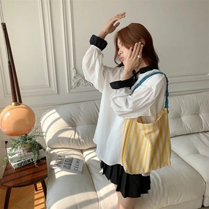 Detail of yellow and white striped canvas tote bag with ruffled shoulder strap detail