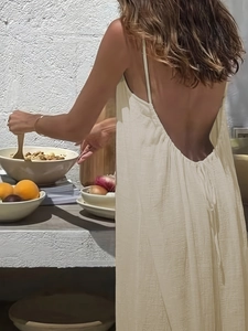 Detailed back view of a cream backless maxi dress featuring pleated fabric and thin straps