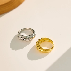 Top view of gold and silver croissant dome rings with twisted metal texture on flat surface