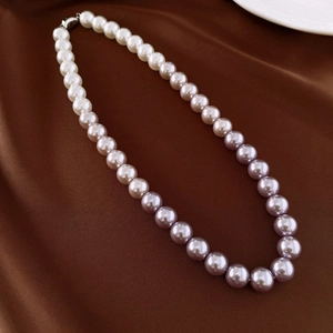 Detail of dual-tone pearl necklace featuring white and purple pearls on satin fabric