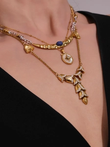 Close-up of layered 18K gold necklaces with blue stone and shell charms on model