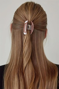 Close-up of brown rugby-shaped hair claw clip on a woman's half-tied hairstyle