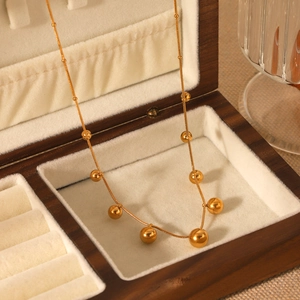 Golden stainless steel snake chain necklace with gold ball pendants in a wooden box