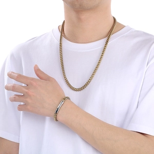 Gros plan sur l'ensemble collier et bracelet gourmette en acier doré sur un mannequin homme
