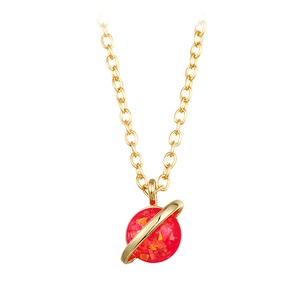 Detailed close-up of golden planet necklace with a sparkling red opal stone and ring