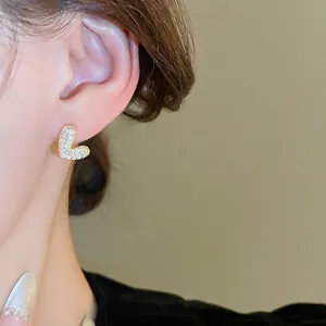 Boucle d'oreille lettre L plaquée or avec zircons portée par un mannequin
