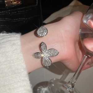 Detail of silver open bangle with pavé crystal butterfly and teardrop charms on wrist