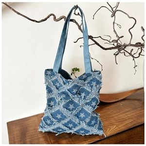 Macro detail of frayed denim patchwork tote bag with star patterns and vintage texture