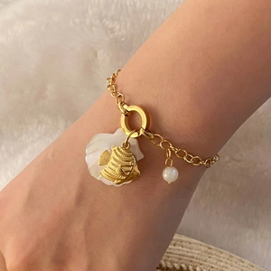 Fashionable gold chain shell bracelet with starfish and turtle charms worn by a model