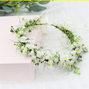 Close-up of white daisies and roses floral crown with silk ribbon on a pink box