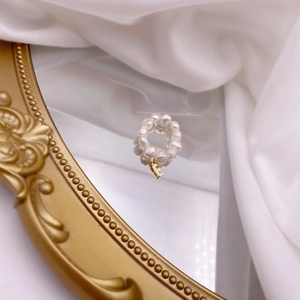 Detail of freshwater pearl ring with a gold letter L pendant on vintage mirror