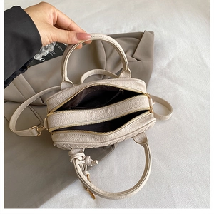Detailed view of beige hand-woven Boston bag with double zippers and golden hardware