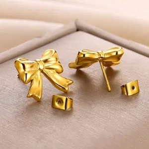 Elegant gold bow-knot stud earrings with polished metallic finish on a textured display box