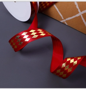Close-up of red polyester ribbon with golden diamond pattern for gift wrapping and DIY