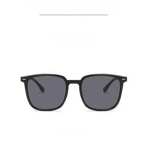 Detail of square black sunglasses with gray lenses and gold hinge accent on white background