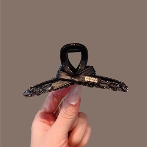 Elegante molletta per capelli a fiocco con cristalli neri, strass e logo dorato