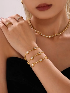 Detailed close-up of 18K gold plated necklace and bracelet set with sparkling zircons
