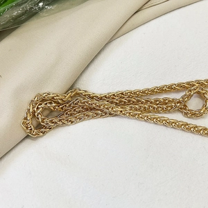 Close-up of bright gold braided metal chain strap for a shell-shaped crossbody bag