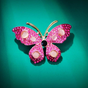 Detailed close-up of butterfly brooch with pink rhinestones and dark cat eye stones